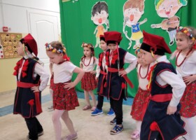 dzieci w strojach krakowiaka na tle zielonej ściany konkurs piosenki