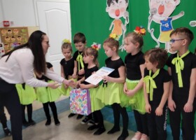 grupa dzieci na tle zielonej dekoracji konkurs piosenki wręczenie dyplomu