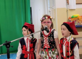 dziewczynka i dwóch chłopców w strojach krakowiaka przy mikrofonie konkurs piosenki