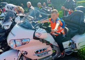 Chłopiec w kamizelce odblaskowej siedzi na motocyklu