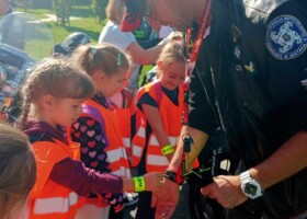 Mężczyzna z motocyklowej watahy zakłada dzieciom odblaski na ręce