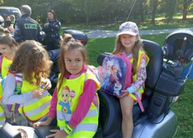 Dziewczynki w kamizelkach odblaskowych siedzą na motocyklu