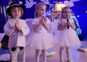 Dziewczynki przebrane za aniołki i chłopiec w przebraniu pasterza podczas Jasełek