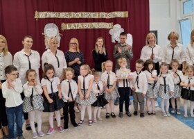 Grupa dzieci z nauczycielami na holu przedszkolnym po odebraniu nagrody w konkursie Polskiej Piosenki