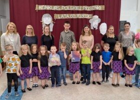Grupa dzieci z nauczycielami na holu przedszkolnym po odebraniu nagrody w konkursie Polskiej Piosenki